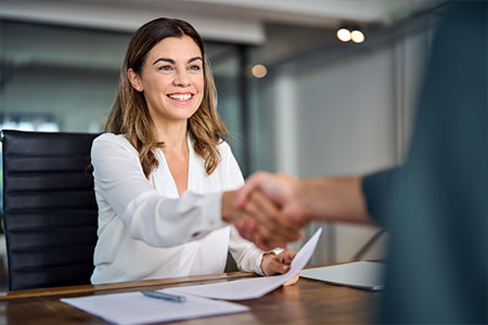 A woman shaking someone's hand in her office