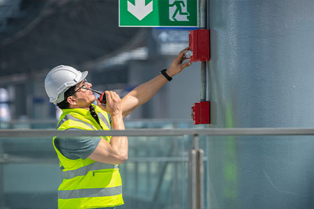 A construction worker testing fire alarms