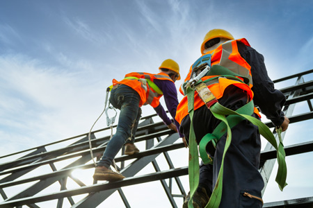 Construction workers climbing scaffolding wearing harnesses