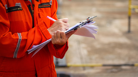 A construction worker writing on a clipboard