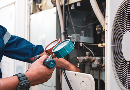 A person checking Refrigerant levels on an air conditioning unit