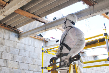 A man in PPE inspecting asbestos