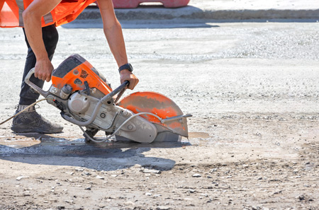 Man using abrasive wheel to cut concrete