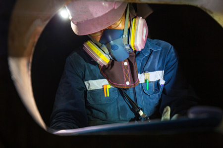 Construction worker in a pipe wearing breathing apparatus 