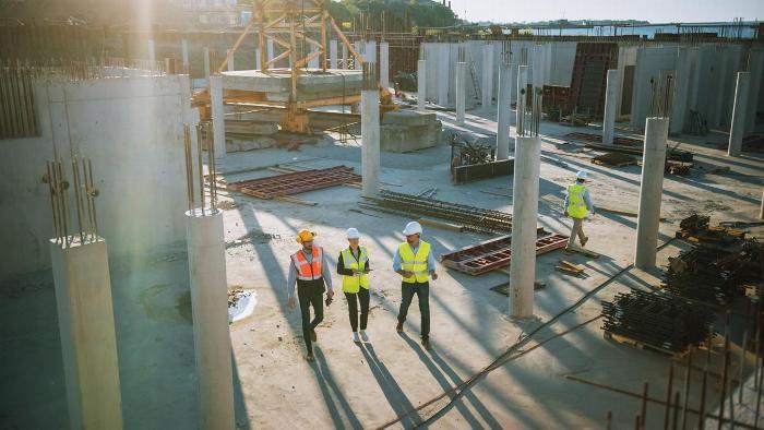 Men wearing High Vis jackets walking through a building site